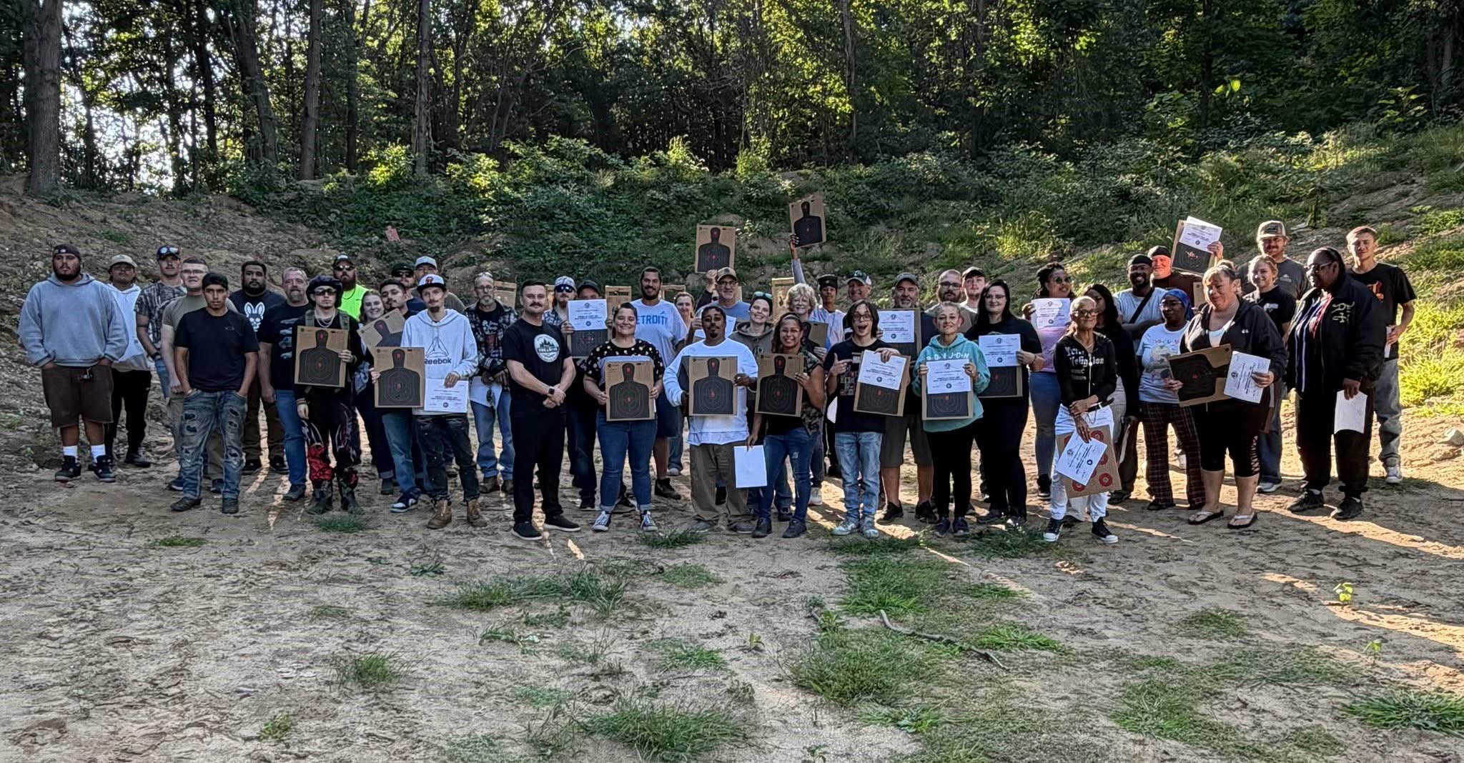 Battle Creek CPL class participants holding targets and certificates outdoors.